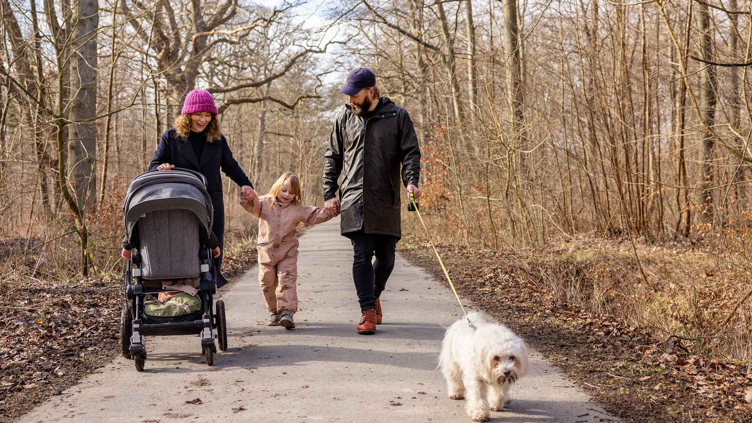 Et forældrepar går tur med barn og hund